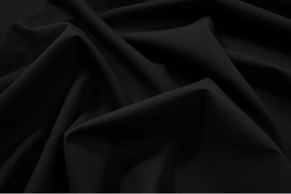 Tkanina wełniana z domieszką poliestru w kolorze czarnym z lekko widoczną kratką